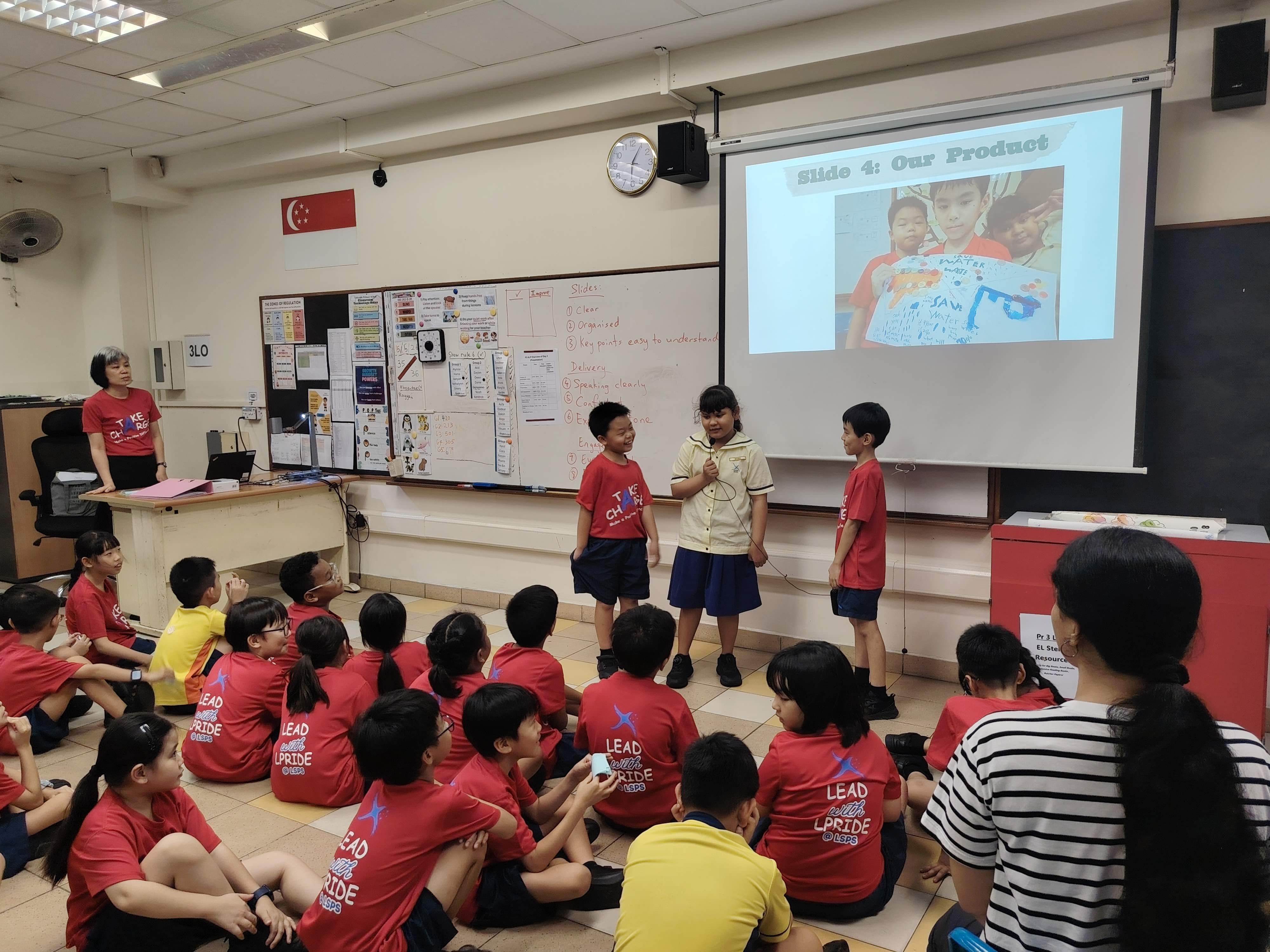 Three students in front of their class giving a presentation showcasing their finished work
